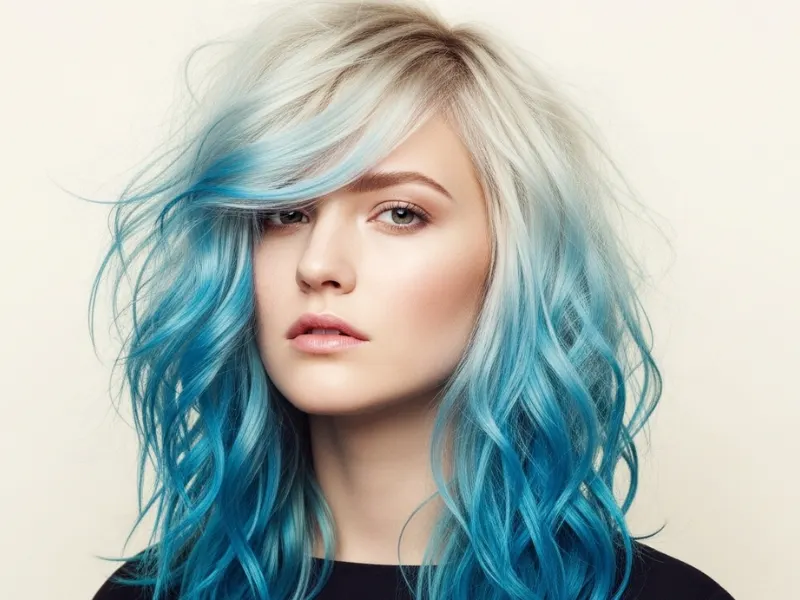 Ash blonde hair with bold blue highlights, styled in loose waves.